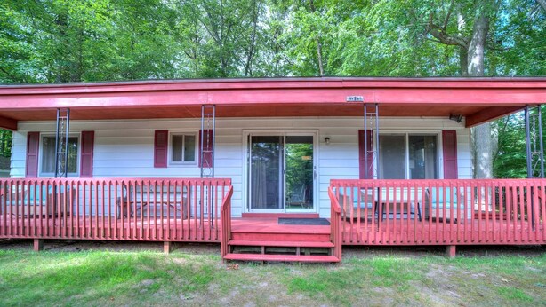 A two-story cabin with a red roof and a covered porch. - Lovely Beach House Rental in Coastal Michigan, for Memorable Getaways to Muskegon (Muskegon)