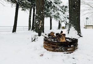 A snow-covered outdoor area with a fire pit surrounded by trees. - Lovely Beach House Rental in Coastal Michigan, for Memorable Getaways to Muskegon (Muskegon)