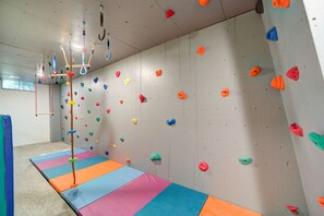 Un gimnasio de escalada con suelo acolchado, presas de colores y cuerdas de seguridad.