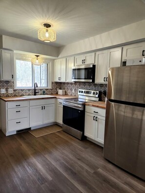 Una cocina moderna con gabinetes blancos, electrodomésticos de acero inoxidable y un salpicadero con diseño.