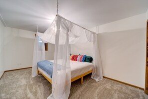 A bedroom with a canopy bed, carpeted floor, and white walls. - Lovely Beach House Rental in Coastal Michigan, for Memorable Getaways to Muskegon (Muskegon)
