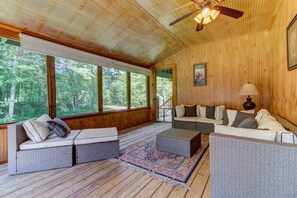 Ein Zimmer mit Holzwandverkleidung, einer Couch, einem kleinen Tisch und einem Deckenventilator.
