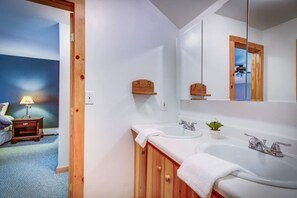 Ein Badezimmer mit zwei Waschbecken, einem großen Spiegel, Holzschränken und einer kleinen Pflanze.