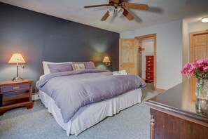 Ein Schlafzimmer mit Bett, Nachttischlampen, einem Holznachttisch, einer Kommode und einem Deckenventilator.