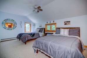 Ein Schlafzimmer mit zwei Betten, einem Deckenventilator, einem Fenster und einem Wandspiegel.