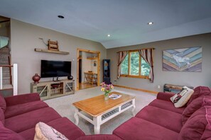 Ein Wohnzimmer mit Fernseher, einem Holztisch, roten Sofas und einem Gemälde an der Wand.