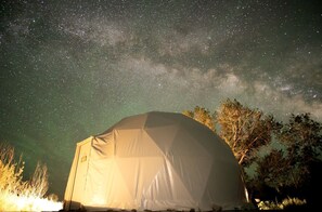 A dome-shaped tent under a starry night sky with visible Milky Way.