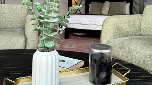 Ein Etagenbett, eine weiße Vase mit grünen Blättern und eine Kerze auf einem Tablett in einem Zeltraum.