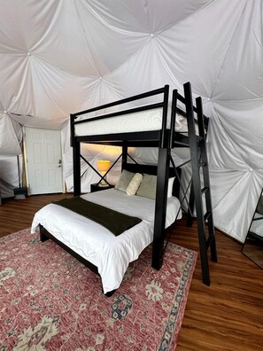A bunk bed in a tent-style room with a patterned rug and a white door.