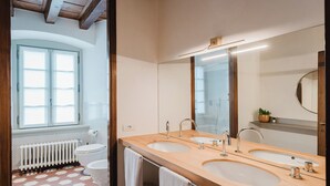 A modern bathroom with two sinks, a large mirror, and a window providing natural light. - Orto Room (Paladina)
