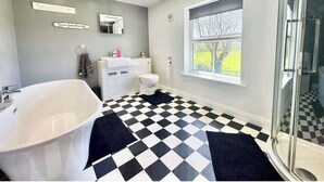 A bathroom with a checkered floor, a white sink, and a glass shower enclosure. - The Old Police House (Louth)
