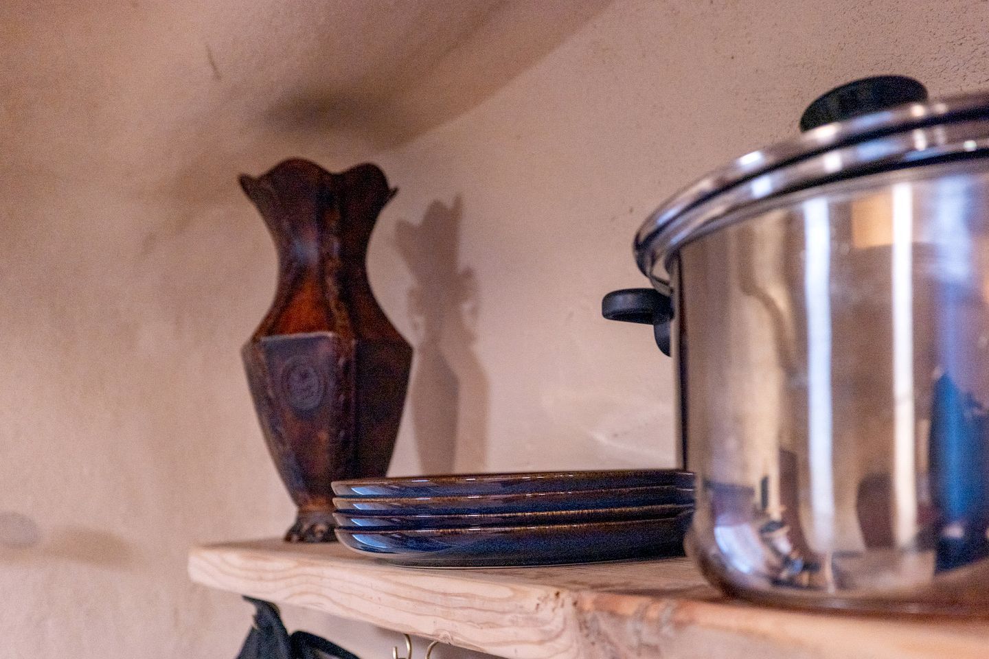 A shelf with a metal pot and a decorative vase.