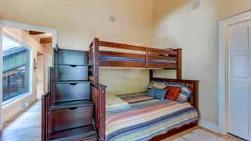 Uma cama beliche com gavetas, uma janela e uma porta.