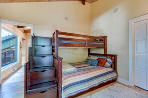 Un lit superposé avec des tiroirs, une fenêtre et une porte.
