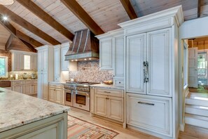 Une cuisine spacieuse avec de hauts plafonds, un grand îlot central et des meubles de rangement intégrés.