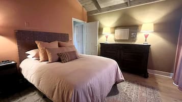 Un dormitorio con cama, mesita de noche, cómoda y lámpara.