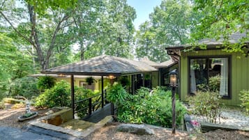 Ein Haus mit einer Veranda, einer Treppe und einem Garten mit unterschiedlichen Pflanzen.
