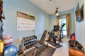Une salle de sport à domicile équipée de matériel d’exercice, d’un rameur, d’haltères et de ballons d’exercice.