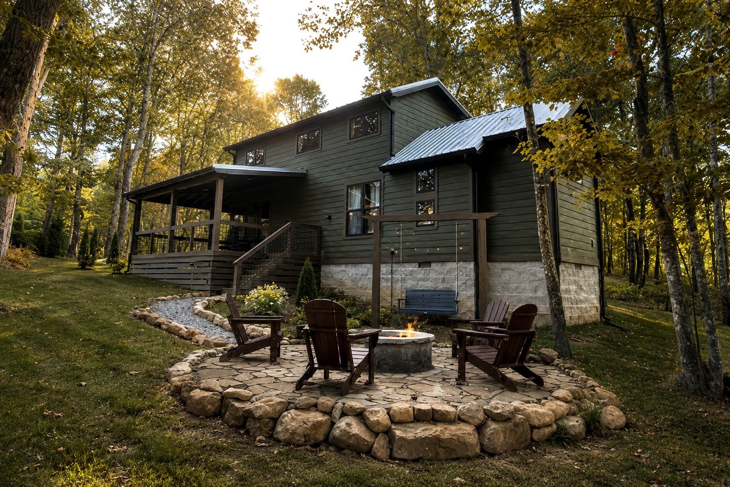 Un chalet rustique doté d’un foyer en pierre et d’un espace salon extérieur, le tout entouré d’une bordure en pierre et d’une terrasse en bois.