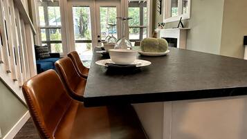 A kitchen with a dark countertop, a white bowl, and a green woven bowl on the table.
