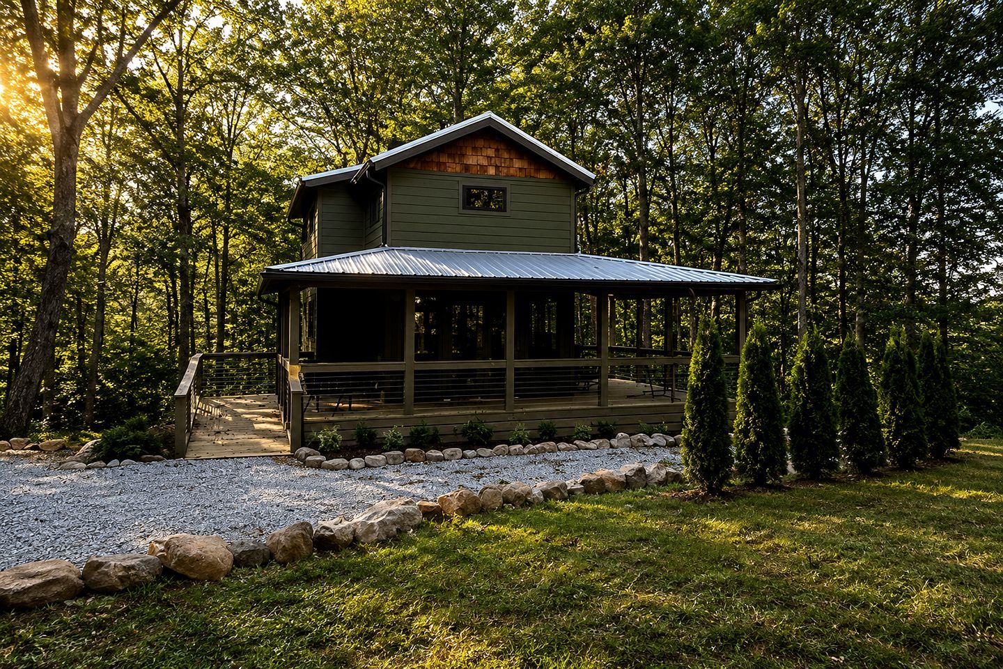 A cabin with a porch, surrounded by trees and a gravel path.