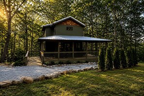 A cabin with a porch, surrounded by trees and a gravel path. - Fully Stocked Cabin Nestled Among the Trees in Tennessee (Monteagle)