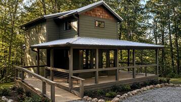 A two-story cabin with a covered deck and a small porch.