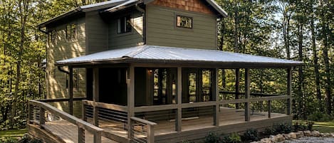 A two-story cabin with a covered deck and a small porch.