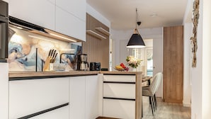 Eine moderne Küche mit weißen Schränken, einer Holz Arbeitsplatte und einer Pendelleuchte.