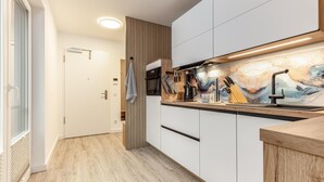 Eine moderne Küche mit Holzboden, weißen Schränken und einer Marmor-Spritzschutzwand.