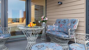 Ein Balkon mit Korbmöbeln, einem Glastisch mit Obst und Blick ins Innere.