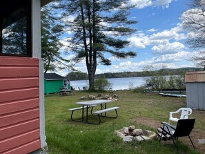 A picnic table, chairs, a shed, and a view of a lake. - Lakefront Secluded Cottage in Northwood, New Hampshire (Northwood)