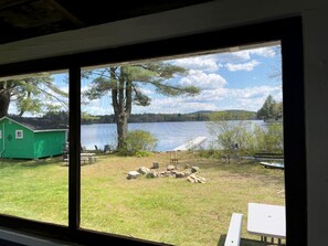 Vista de un lago con un cobertizo verde y una zona de fuego.