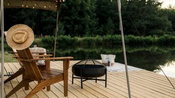 A wooden deck with a chair, a grill, and a table.