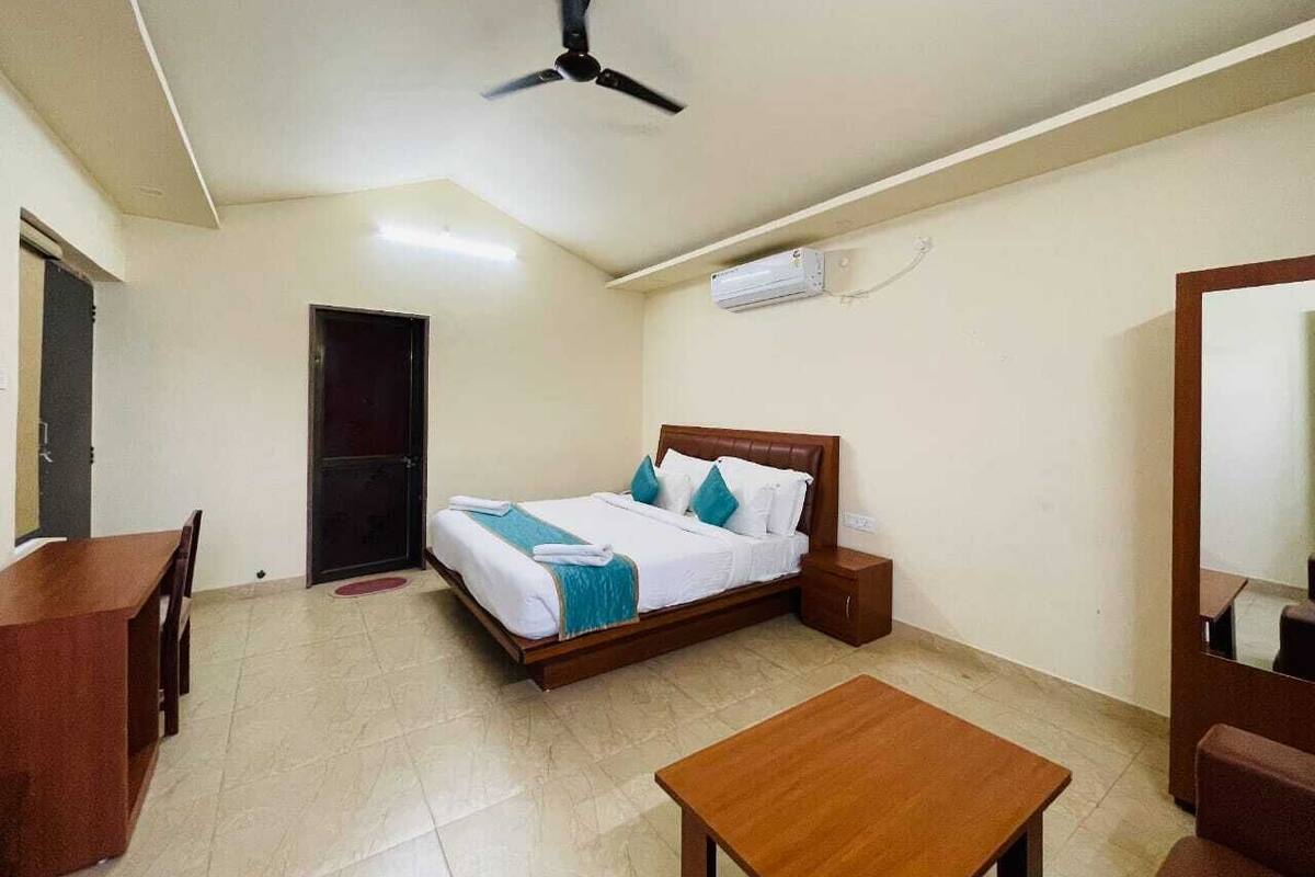 A hotel room with a bed, bedside table, and a desk with chairs.