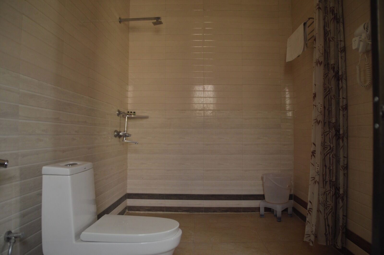 Et badeværelse med toilet, brusebad og toiletpapirholder.