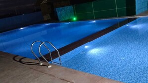 En swimmingpool med en metalstige og en flisebelagt kant.