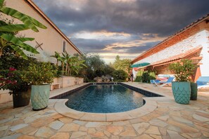 A swimming pool with stone tiles, surrounded by potted plants and a stone wall. - Domaine de Beaufort (Saint-Front-de-Pradoux)
