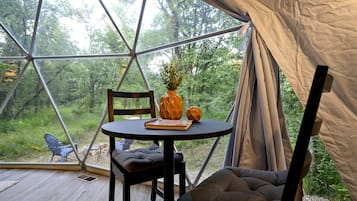 A tent with a round table, a chair, and a cushion inside.