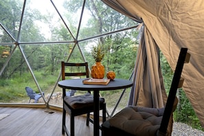 A tent with a round table, a chair, and a cushion inside.