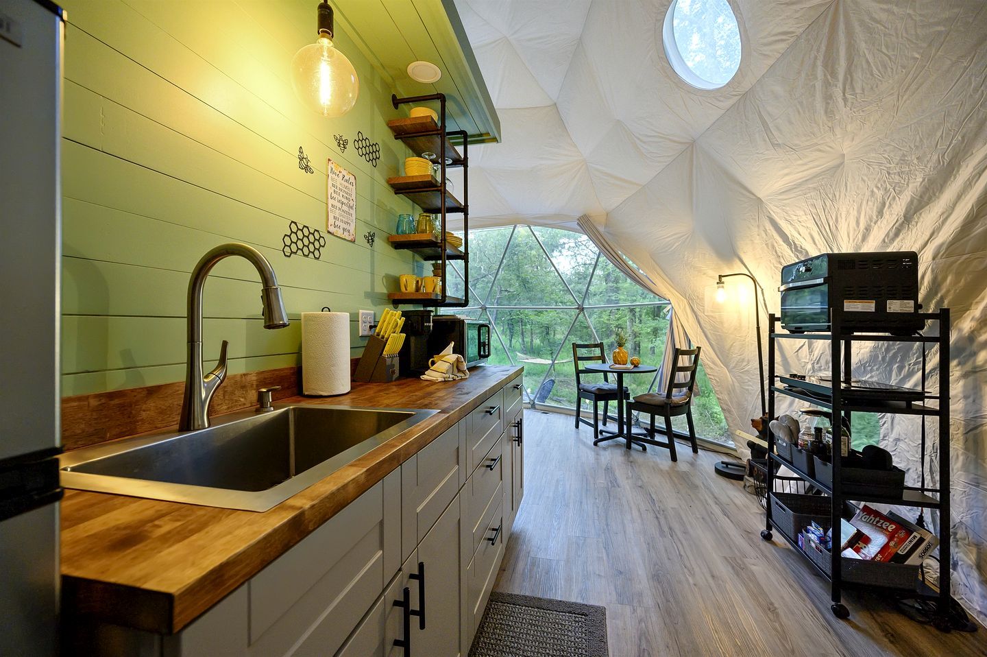 A kitchen with a wooden countertop, a sink, and a dining area with chairs and a table.