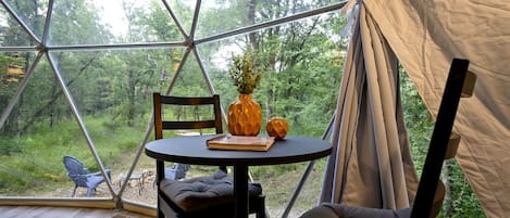 A tent with a round table, a chair, and a cushion inside.