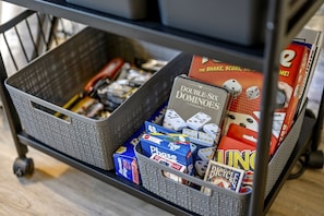A storage cart with various board games, including dominoes and a game called 'Bicycle.'