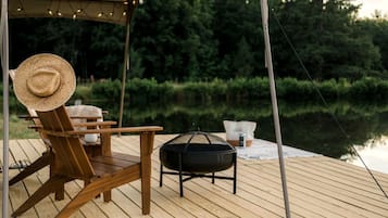 A wooden deck with a chair, a grill, and a table.