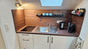 Une cuisine compacte dotée d’une cuisinière intégrée, d’un évier et de placards de rangement.