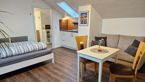 Un espace de vie compact comprenant une chambre en mezzanine, un coin repas et une kitchenette.