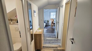 Un couloir doté d’un plancher en bois, d’un banc en bois et donnant sur une salle à manger.