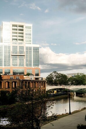 A modern building with a glass facade, a brick base, and a bridge over a water body.