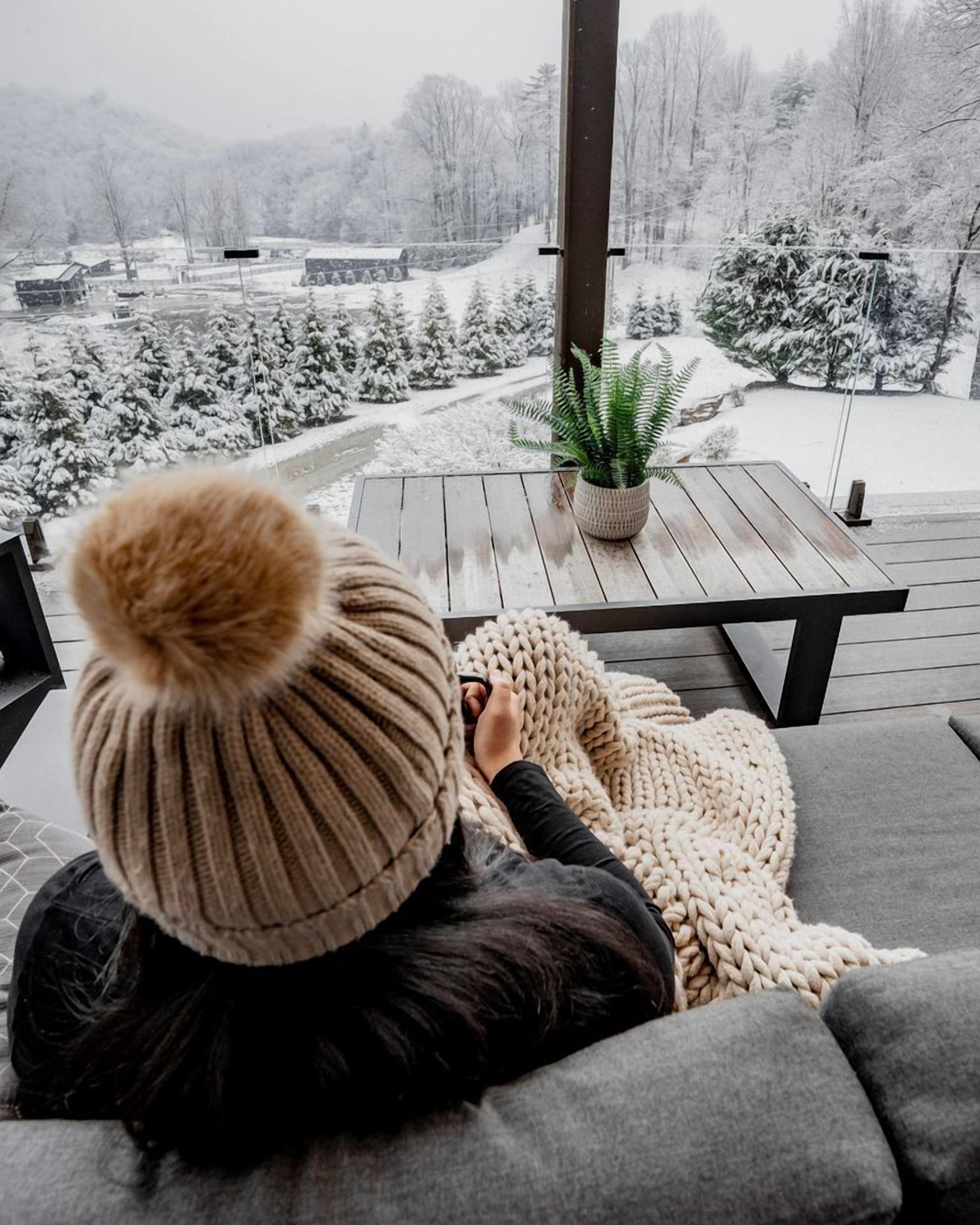 A person sitting on a sofa with a view of a snowy landscape.