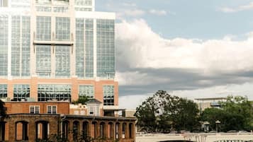 A modern building with a glass facade, a brick base, and a bridge over a water body.